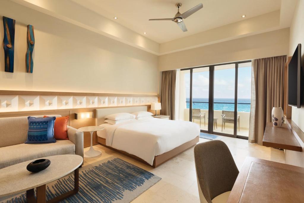 Habitación premium con cama king, sofá y balcón con vista al mar en hotel de lujo en Cancún